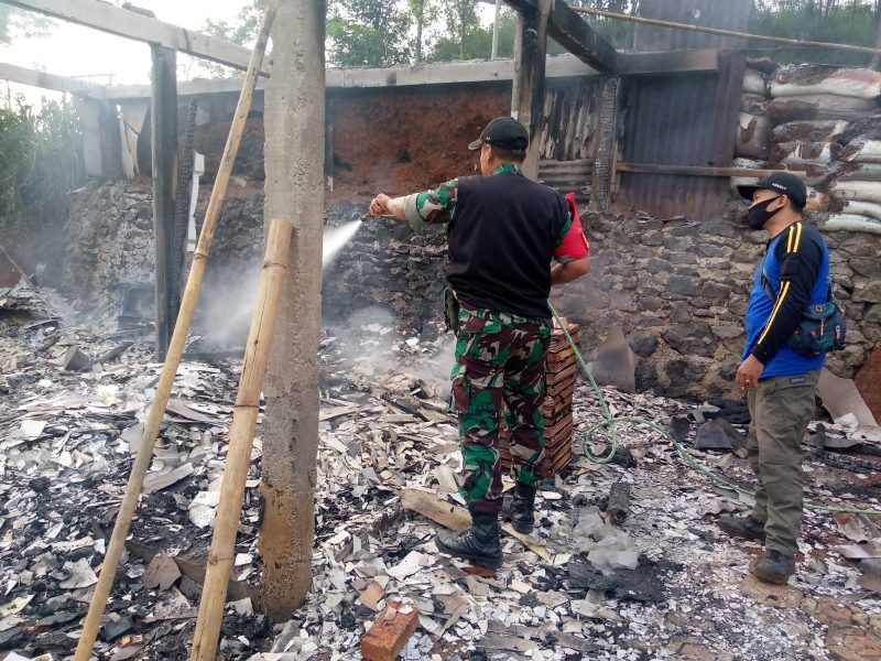 PENDINGINAN : Salah seorang petugas dari Babinsa saat melakukan pendinginan terhadap rumah yang terbakar di Kampung Nangela RT (05/ 08) Desa/Kecamatan Jampangtengah