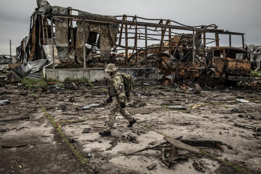 Seorang tentara Ukraina berjalan melewati gudang yang hancur tempat pasukan Rusia