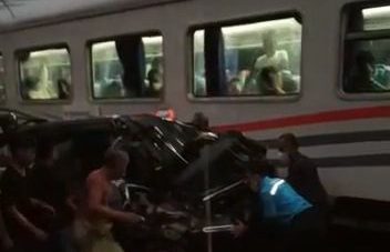 Warga saat mengevakuasi mobil yang tertabrak Kereta Api
