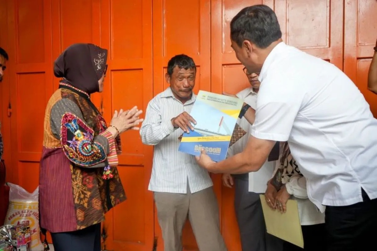 Menteri Sosial Tri Rismaharini memberikan bantuan kepada warga Arcamanik, Jotua Sinurat (51) yang viral karena berniat menjual sepeda seharga Rp200.000 untuk melunasi biaya sekolah anaknya di Bandung, Jawa Barat, Rabu (20/9/2023). 