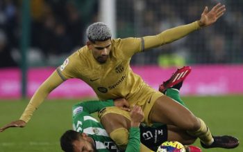 Pesepak bola Barcelona Ronald Araujo (atas) berebut bola dengan pemain Real Betis Borja Iglesias dalam laga Liga Spanyol di Stadion Benito Villamarin, Spanyol, Kamis (2/2/2023) dini hari. Barcelona tetap kokoh di puncak klasemen setelah mengalahkan tuan rumah Real Betis 2-1 dan mengumpulkan poin 50. (Reuters-Marcelo Del Pozo​​​​​​​/nym)