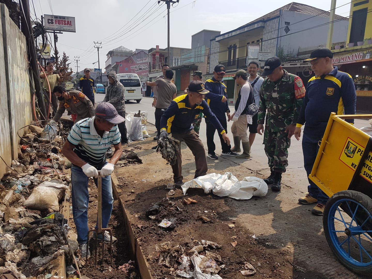 DIBERSIHKAN : warga dan Pemdes Cimangkok, Kecamatan Sukalarang, saat membersihkan sampah di sepanjang Jalan Nasional, Sukabumi - Cianjur, Kilometer 12 pada Jumat (03/11).(FOTO : DENDI RADAR SUKABUMI)