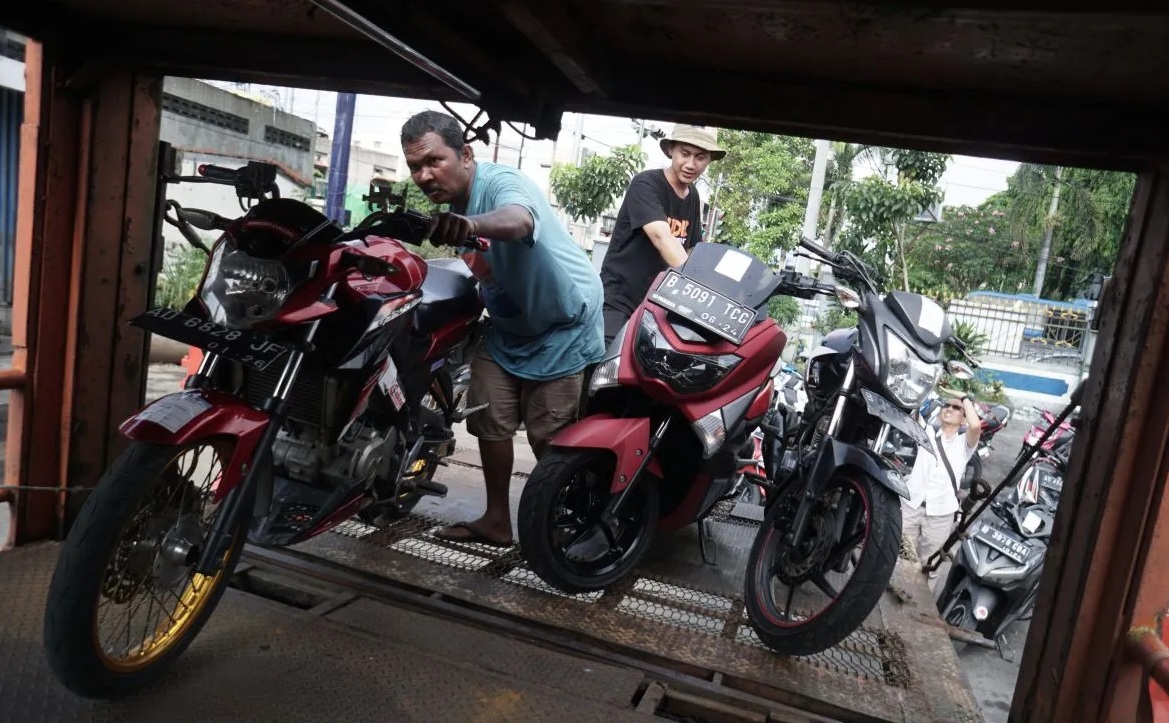 Pekerja menaikkan sepeda motor peserta program mudik balik gratis ke atas truk di Terminal Tirtonadi, Solo, Jawa Tengah, Rabu (26/4/2023).