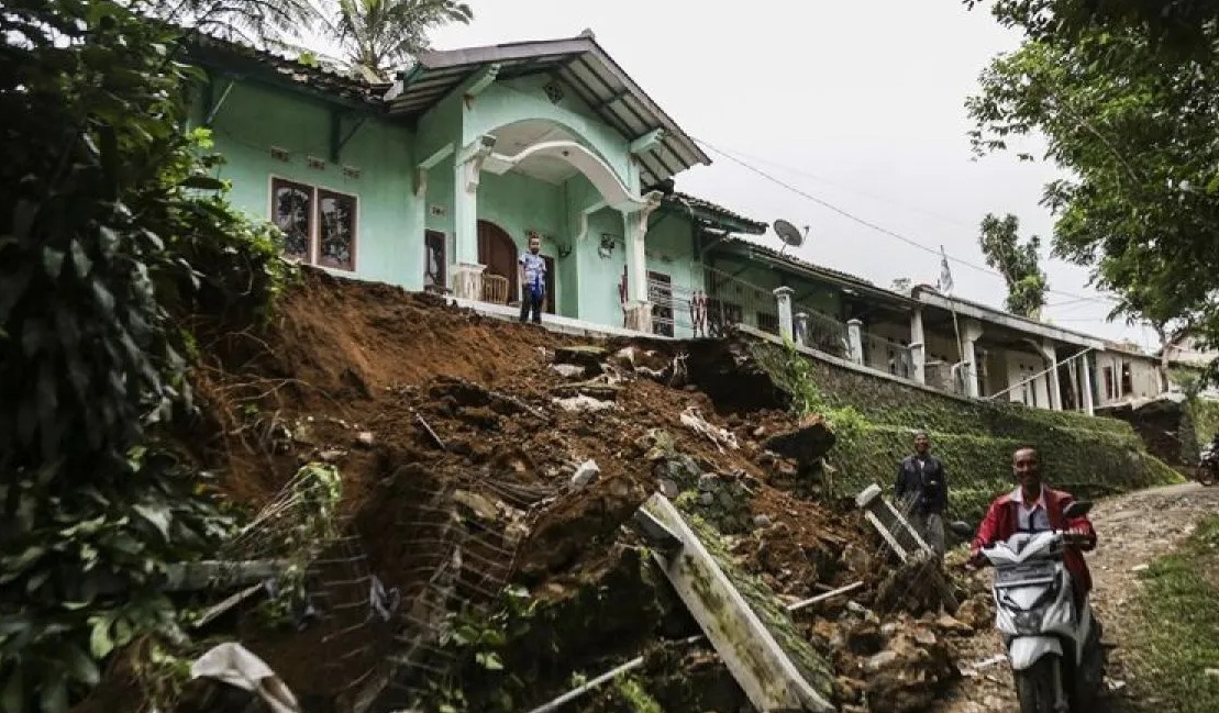 Warga melintas di reruntuhan tanah di Pasir Masigit, Desa Cipeuteuy, Kabandungan, Kabupaten Sukabumi, Jawa Barat, Sabtu (9/12/2023). (Henry Purba)