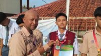 BANGGA: Wakil Kepala Bidang Kesiswaan SMKN 2 Kota Sukabumi, Slamet Widodo memberikan ucapan selamat kepada salah satu siswa yang meraih juara pada ajang Silat Unlip Championship 2024 usai melaksanakan upacara bendera.