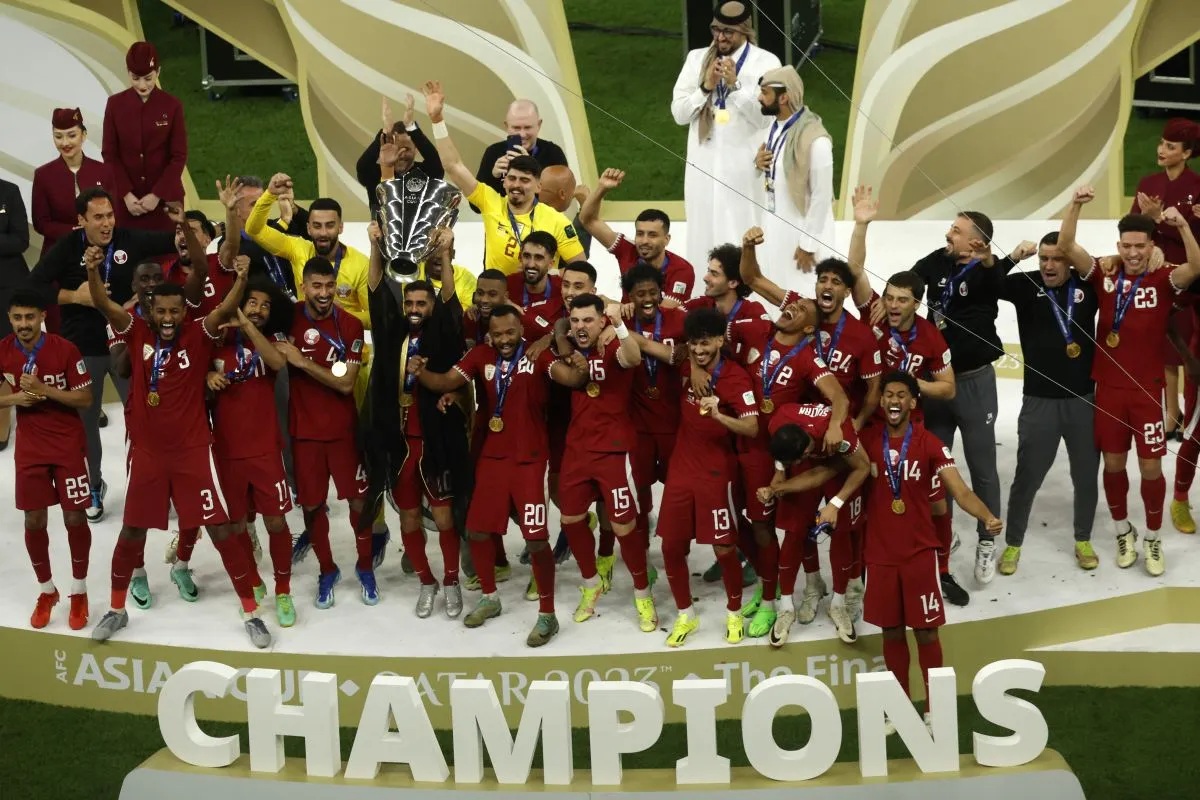 Pemain Qatar Hassan Al-Haydos mengangkat trofi juara Piala Asia 2023 bersama rekan-rekannya yang merayakan keberhasilan Qatar mempertahankan gelar juara Piala Asia setelah menaklukkan Yordania dalam final di Stadion Lusail di Lusail, sebelah utara Doha, Qatar, pada 10 Februari 2024. (AFP/KARIM JAAFAR)