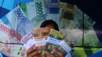 Warga menunjukan uang hasil penukaran di mobil kas keliling Bank Indonesia. (Andri Saputra)