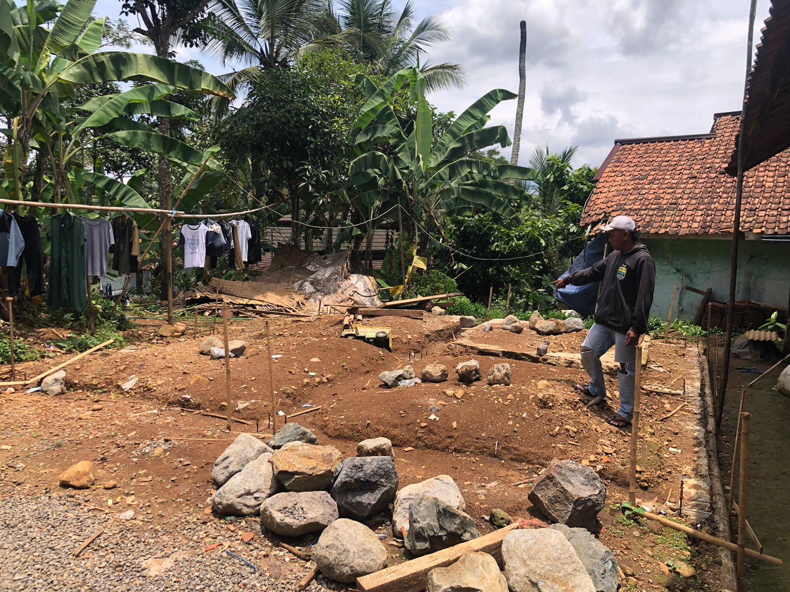 KECEWA : Salah seorang warga saat menunjukan pembangunan pondasi untuk hunian tetap yang diberhentikan bagi penyintas bencana retakan tanah di Kampung Jati, Desa Mekarsari, Kecamatan Nyalindung, Kabupaten Sukabumi.(FOTO : DENDI/RADAR SUKABUMI)