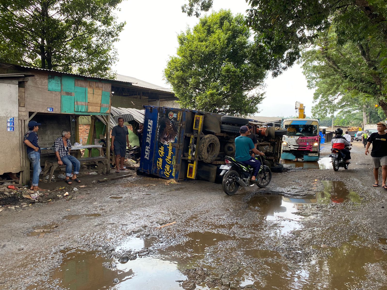 TERJUNGKAL : Kondisi truk bermuatan kayu log, saat terjungkal di ruas Jalan Raya Panggeleseran - Babakan, Kecamatan Cikembar, Kabupaten Sukabumi pada Rabu (27/03) pagi.(FOTO : DENDI/RADAR SUKABUMI)
