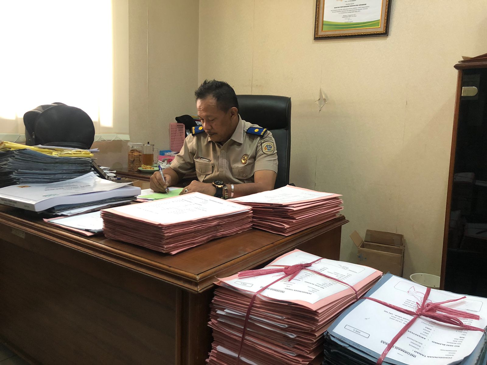 DITANDATANGANI : Kepala Seksi Pengadaan Tanah dan Pengembangan BPN Kabupaten Sukabumi, Enang saat menandatangani sertifikat program PTSL di ruang kerjanya.