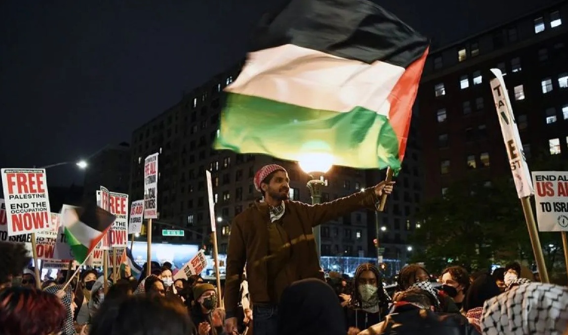 Seorang pria mengibarkan bendera Palestina dalam aksi unjuk rasa pro-Palestina yang digelar di luar Universitas Columbia di New York, Amerika Serikat, Selasa (23/4/2024). Xinhua.