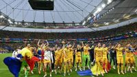 Para pemain dan staf Rumania merayakan kemenangan grup mereka di lapangan setelah pertandingan sepak bola Grup E UEFA Euro 2024 antara Slovakia dan Rumania di Frankfurt Arena di Frankfurt am Main pada 26 Juni 2024. (AFP/Javier Soriano)