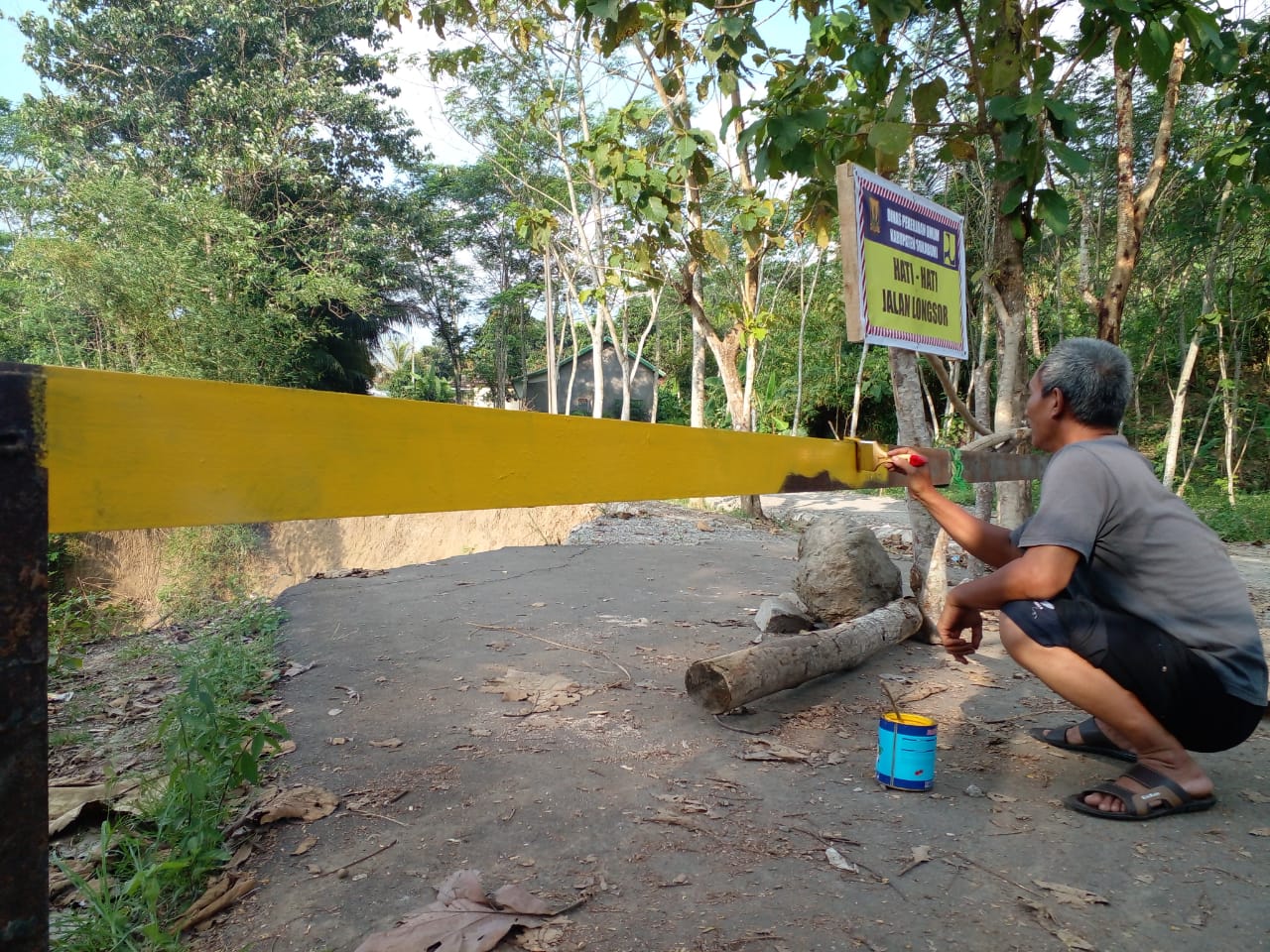 MENGECET : Salah seorang warga pada saat melakukan pengecetan di lokasi pamasangan pembatas jalan.