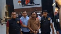 Pegawai KPK gadungan berinisial YS (baju coklat) meninggalkan Gedung Merah Putih KPK dengan dikawal petugas dari Polres Kabupaten Bogor pada Jumat dini hari (26/7/2024). (Fianda Sjofjan Rassat)