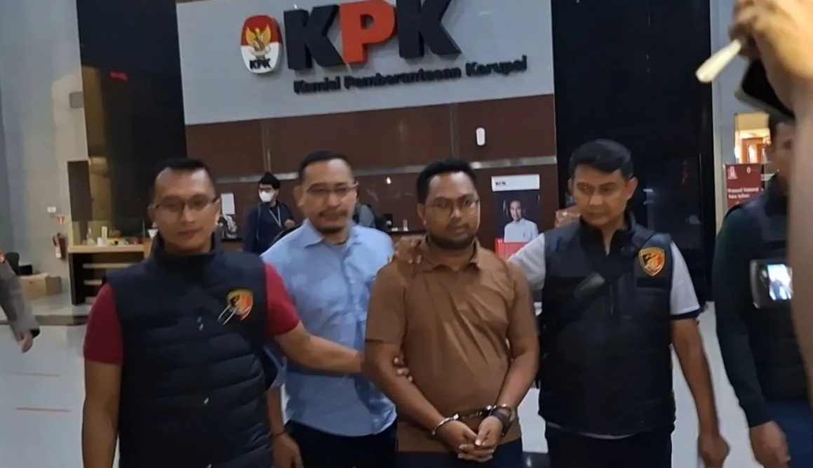 Pegawai KPK gadungan berinisial YS (baju coklat) meninggalkan Gedung Merah Putih KPK dengan dikawal petugas dari Polres Kabupaten Bogor pada Jumat dini hari (26/7/2024). (Fianda Sjofjan Rassat)