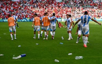 Pemain depan Argentina Giuliano Simeone (kedua dari kanan) melihat botol-botol bekas minuman yang dilemparkan para pendukung Maroko ke lapangan saat pertandingan penyisihan grup B Olimpiade Paris 2024 di Geoffroy-Guichard Stadium, Saint-Etienne, Rabu (24/7/2024). (AFP/ARNAUD FINISTRE)