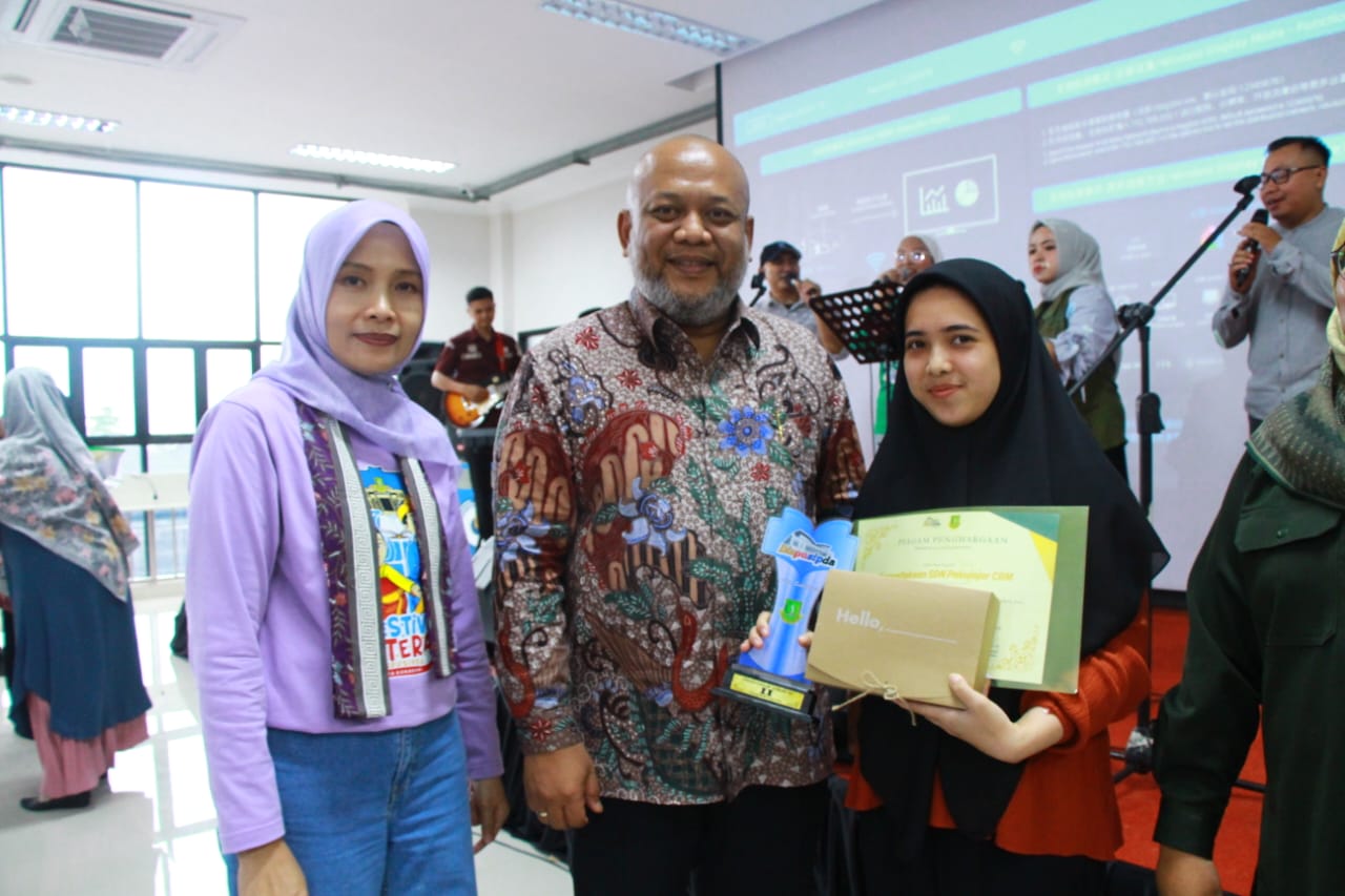 JUARA : Pengelola Harian Perpustakaan SDN Pakujajar CBM, Harmi Hikmatiar, menunjukan piala sekaligus piagam penghargaan dari Perpustakaan Umum Kota Sukabumi sebagai sekolah terbaik ke-2 tingkat SD/MI se-Kota Sukabumi.
