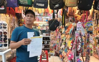 MENUNJUKAN : Salah seorang warga pasar semi modern Palabuhanratu saat menujukan tagihan kios.(FOTO : NANDI/ RADARSUKABUMI)