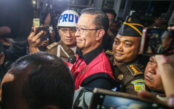 Menteri Perdagangan tahun 2015-2016 Thomas Lembong dibawa menuju mobil tahanan di Kejaksaan Agung, Jakarta, Selasa (29/10/2024). (Miftahul Hayat/ Jawa Pos)