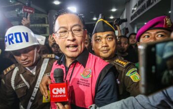 Menteri Perdagangan tahun 2015-2016 Thomas Lembong dibawa menuju mobil tahanan di Kejaksaan Agung, Jakarta, Selasa (29/10/2024). (Miftahul Hayat/Jawa Pos)