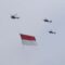 Tiga helikopter TNI terbang dengan mengibarkan bendera Merah Putih di kawasan Monas, Jakarta, Selasa (5/10/2021).