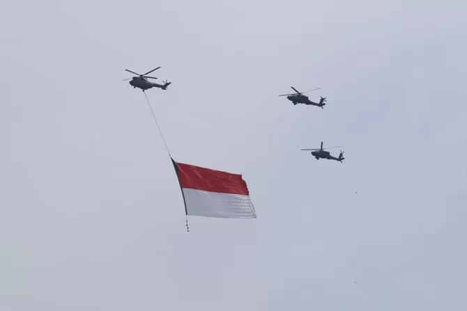 Tiga helikopter TNI terbang dengan mengibarkan bendera Merah Putih di kawasan Monas, Jakarta, Selasa (5/10/2021).