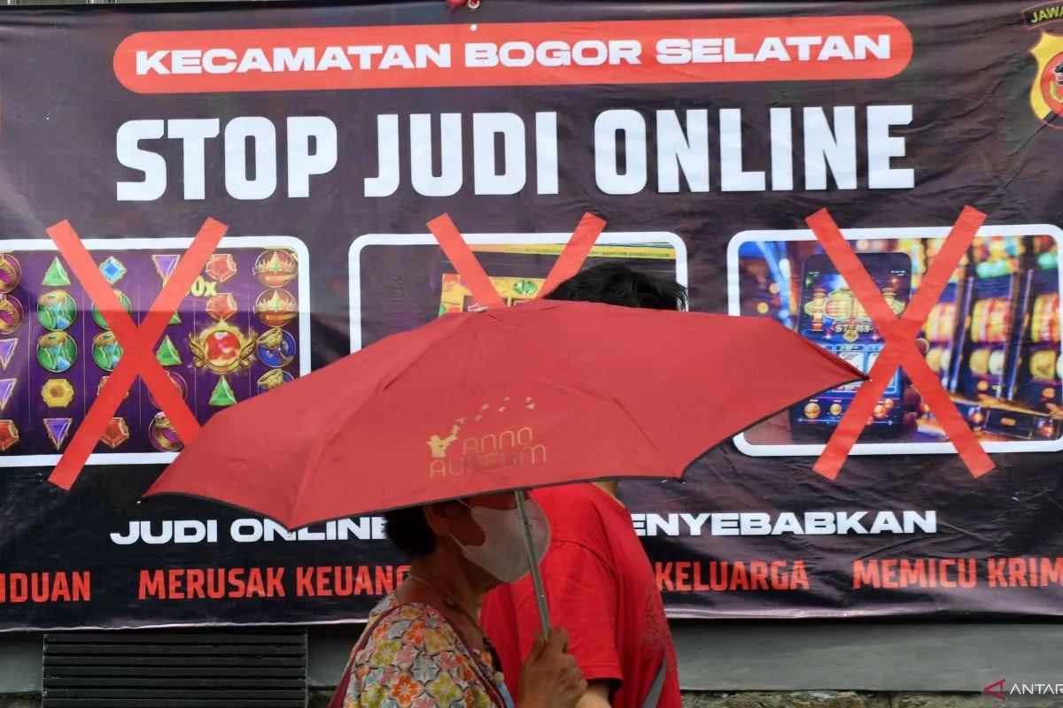 Warga berjalan di depan spanduk sosialisasi larangan judi online di Kantor Kecamatan Bogor Selatan, Kota Bogor, Jawa Barat, Senin (1/7/2024). (ARIF FIRMANSYAH)