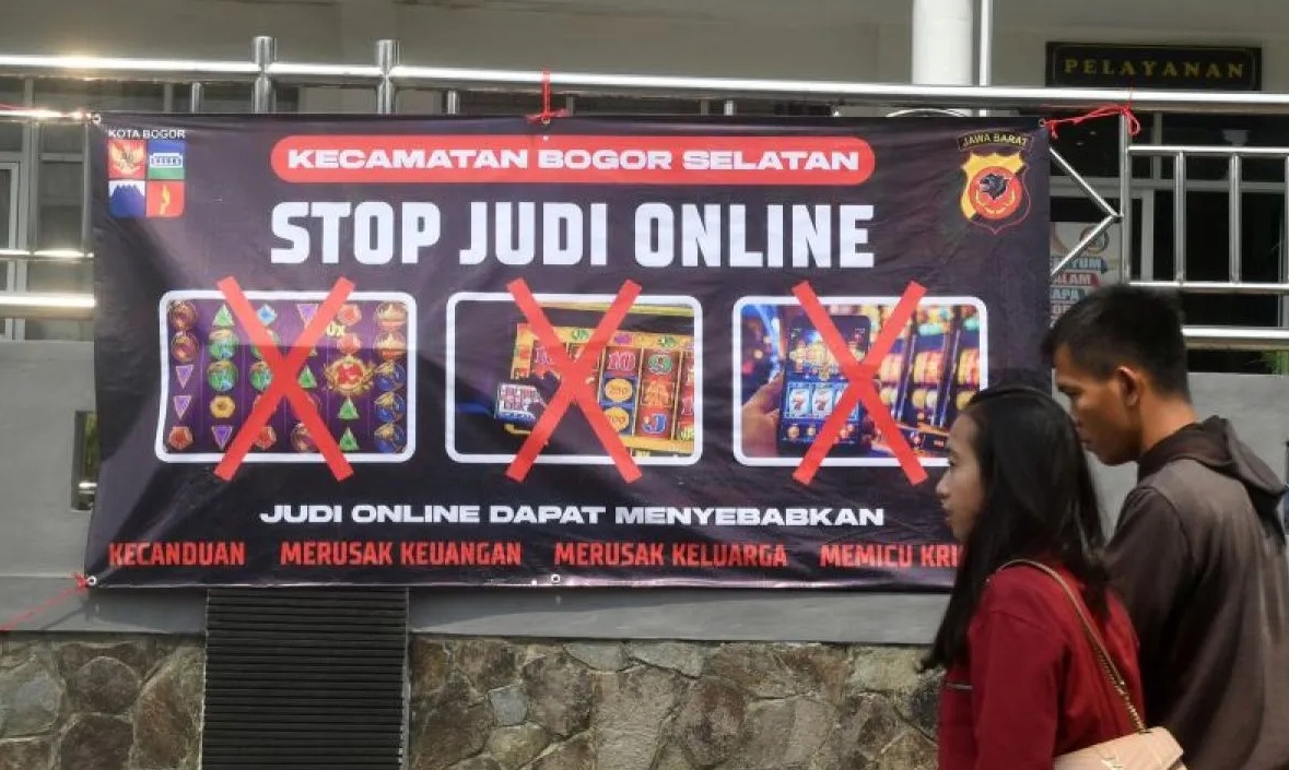 Warga berjalan di depan spanduk sosialisasi larangan judi online di Kantor Kecamatan Bogor Selatan, Kota Bogor, Jawa Barat, Senin (1/7/2024). (Arif Firmansyah)