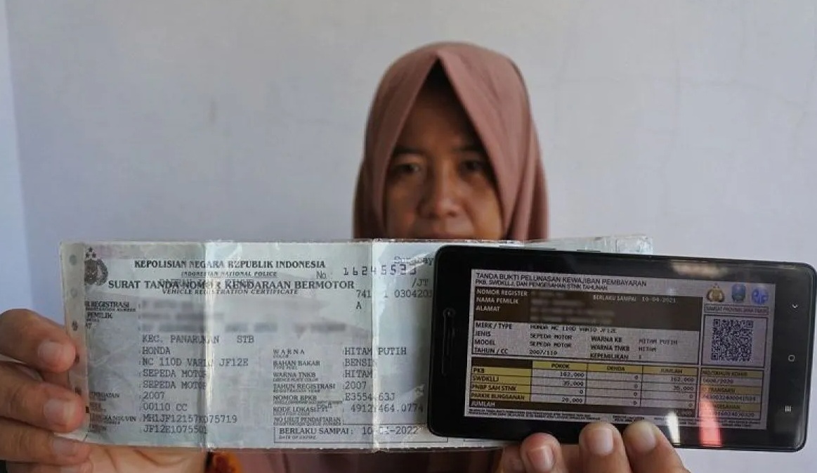 Seorang warga memperlihatkan bukti pelunasan pajak kendaraan bermotor yang dibayar secara daring atau online dari rumah di Panarukan, Situbondo, Jawa Timur.