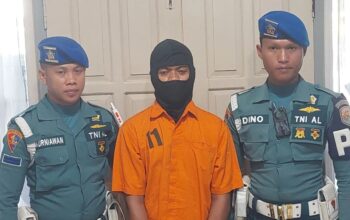 Tersangka pelaku pembunuhan Kesia Irena Yola Lestaluhu dikawal dua personel Pomal Lantamal XIV Sorong di Kota Sorong (15/1/2025). (Yuvensius Lasa Banafanu)