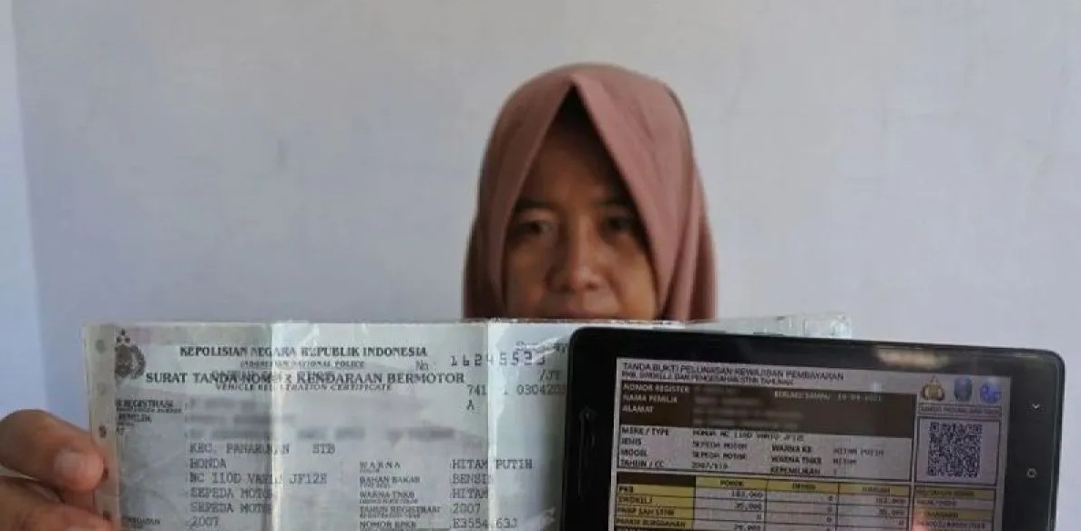 Seorang warga memperlihatkan bukti pelunasan pajak kendaraan bermotor yang dibayar secara daring atau online dari rumah di Panarukan, Situbondo, Jawa Timur. (Seno)