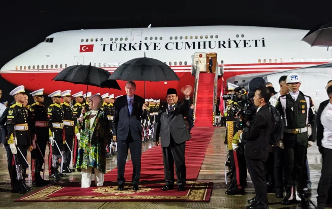 Presiden RI Prabowo Subianto dan Presiden Turki Recep Tayyip Erdogan beserta Ibu Negara Emine Erdogan berbagi payung saat ketibaan Erdogan di Pangkalan TNI AU Halim Perdanakusuma, Jakarta, Selasa (11/10/2025) malam. (Mentari Dwi Gayati)