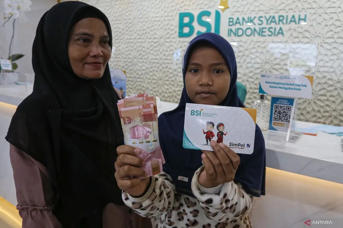 Seorang pelajar didampingi orangtuanya memperlihatkan uang tunai bantuan dana Program Indonesia Pintar (PIP) usai pencairan di Bank Syariah Indonesia (BSI) di Banda Aceh, Aceh, Rabu (3/4/2024). (Khalis Surry)