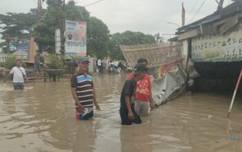 Banjir setinggi lutut orang dewasa masih menggenangi ruas jalan utama penghubung wilayah Kota dengan Kabupaten Bekasi di Desa Sriamur, Kecamatan Tambun Utara, Selasa siang. (Pradita Kurniawan Syah).