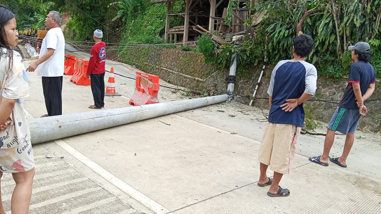 TUMBANG : Tiang listrik tumbang hingga menutupi badan jalan provinsi, tepatnya di Kampung Cisayar, RT 04/RW 08, Desa Mekarsari, Kecamatan Nyalindung, Kabupaten Sukabumi, pada Kamis (20/03) siang.(FOTO : UNTUK RADAR SUKABUMI)