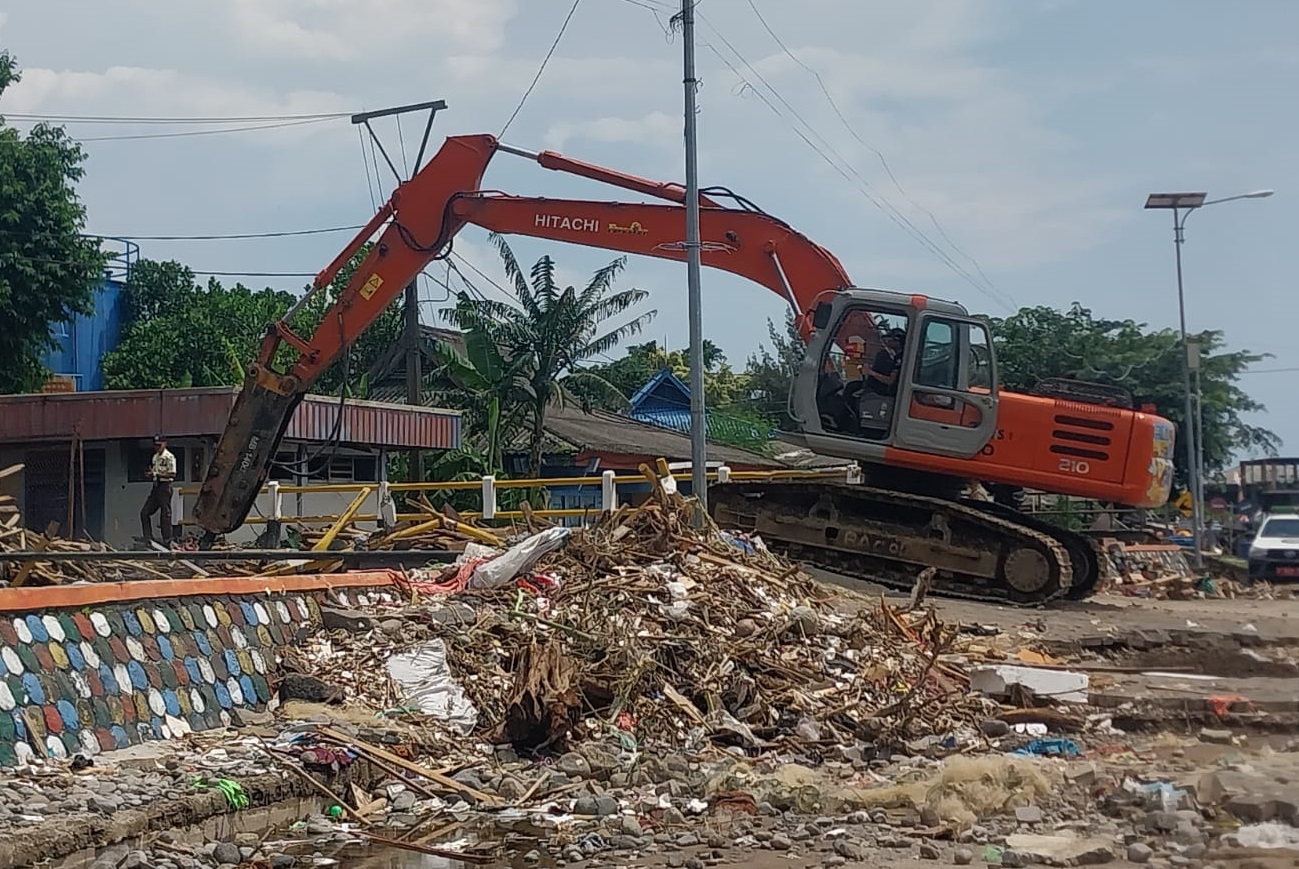 Alat berat melakukan upaya pembongkaran jembatan yang melintasi sungai Cipalabuan akses warga menuju area Dermaga PPN Palabuhanratu. Minggu (9/3/2025).(FOTO : NANDI/ RADARSUKABUMI)
