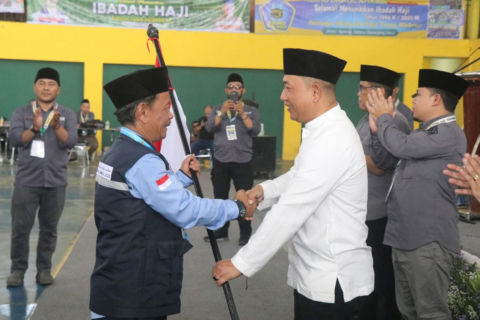 DIBERANGKATKAN : Wakil Bupati Sukabumi, Andreas saat menyerahkan bendera merah putih kepada Ketua Kloter 18 Lukman Hakim di Komplek Pusbangdai Cikembang, Desa Sukamulya, Kecamatan Cikembar, Kabupaten Sukabumi pada Jumat (9/5) siang.(FOTO : UNTUK RADAR SUKABUMI)