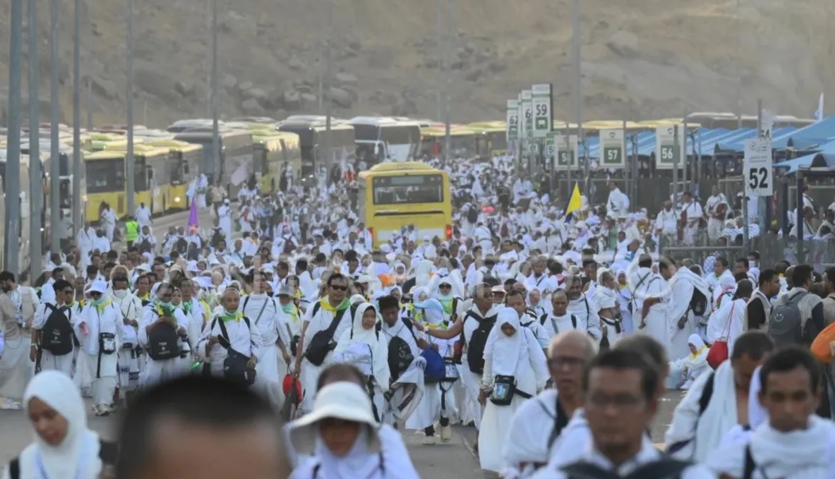 Jamaah haji dari berbagai negara termasuk Indonesia berjalan kaki di samping deretan bus yang tidak bisa bergerak karena terjebak kemacetan di Muzdalifah, Makkah, Arab Saudi, Jumat (6/6/2025).
