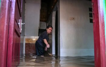 Warga membersihkan rumahnya saat banjir merendam kawasan permukiman di Kramat Jati, Cawang, Jakarta, Senin (7/7/2025). (Sulthony Hasanuddin)