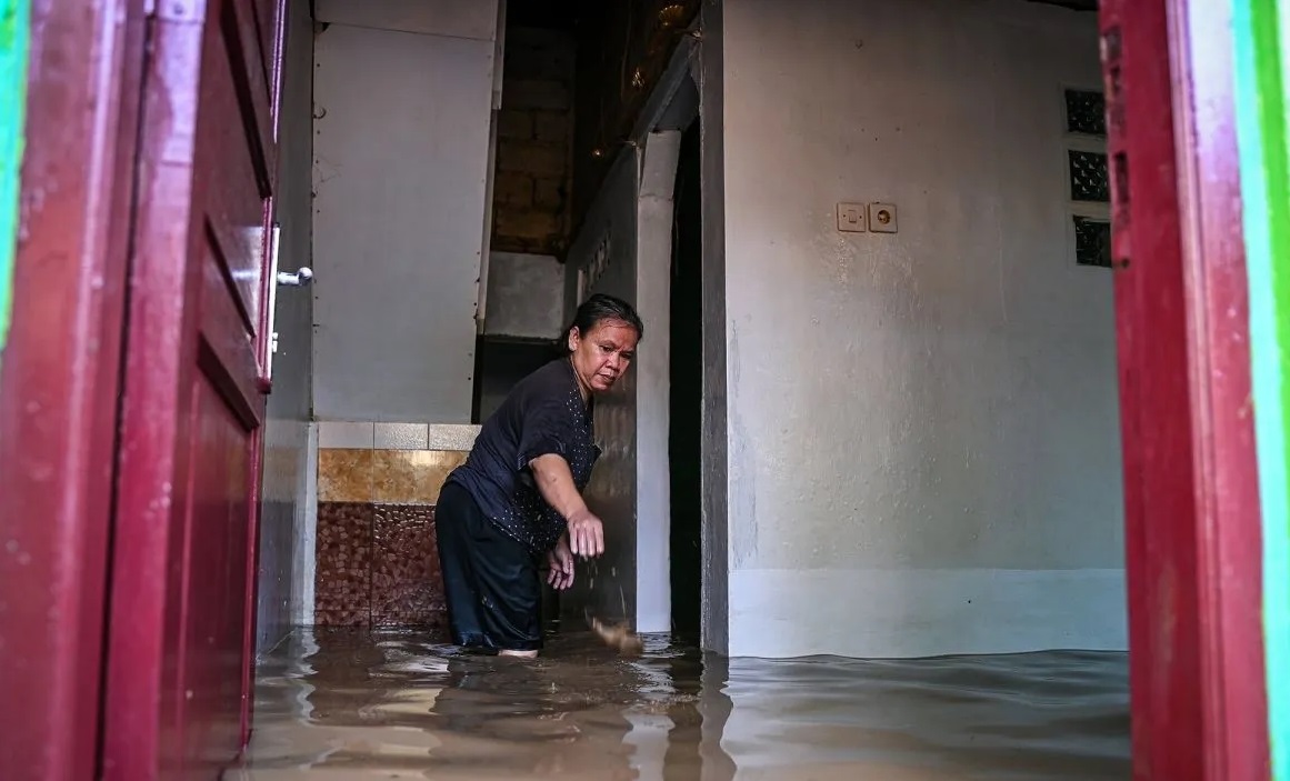 Warga membersihkan rumahnya saat banjir merendam kawasan permukiman di Kramat Jati, Cawang, Jakarta, Senin (7/7/2025). (Sulthony Hasanuddin)