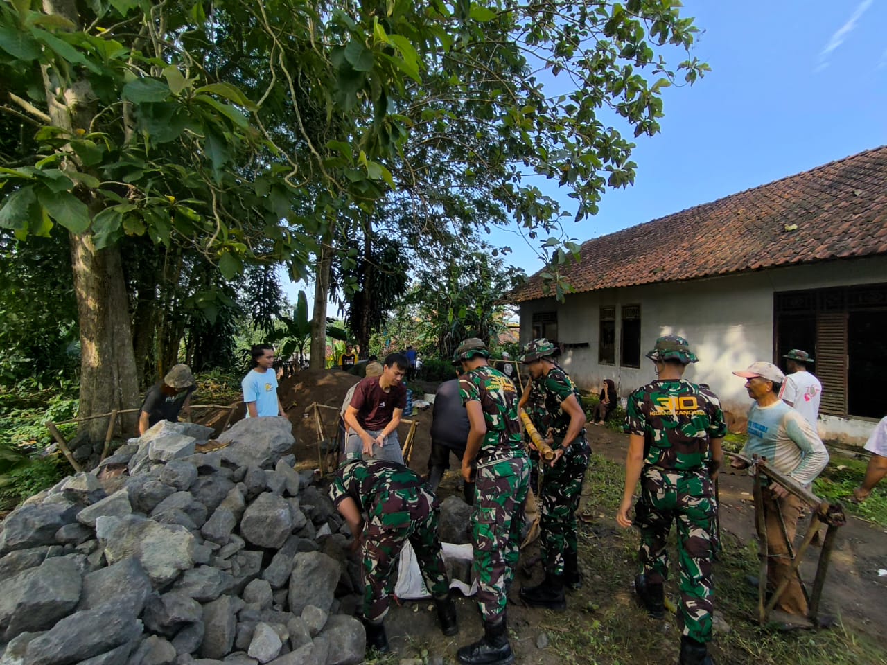 Warga dan TNI kompak bergotong royong membangun saluran drainase di Kampung Cikembar, Jumat (4/7/2025).