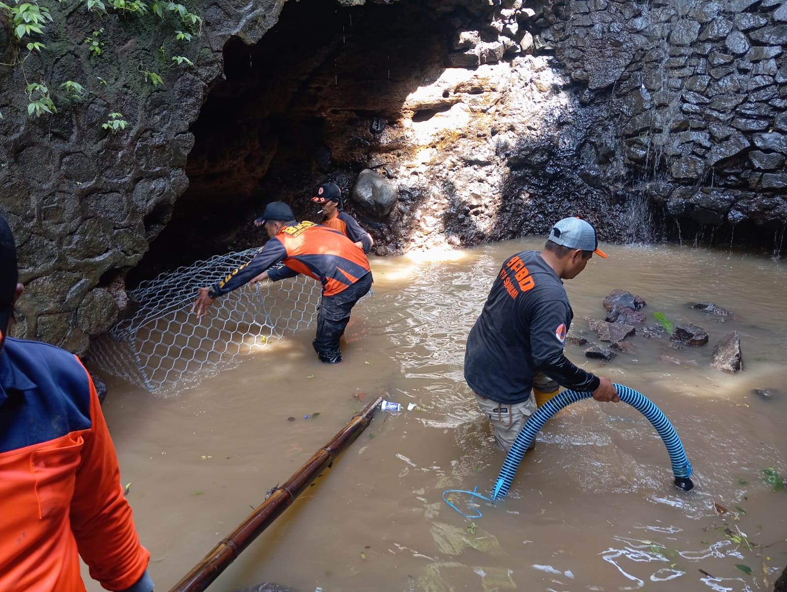 Personel BPBD, DPUTR, dan warga bergotong royong memasang bronjong sebagai upaya penguatan tebing di lokasi rawan longsor.