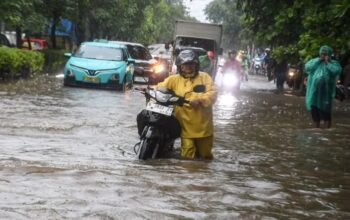 Warga mendorong motornya yang mogok saat melintasi banjir di kawasan Sunter, Jakarta, Senin (12/1/2026).(Muhammad Adimaja)