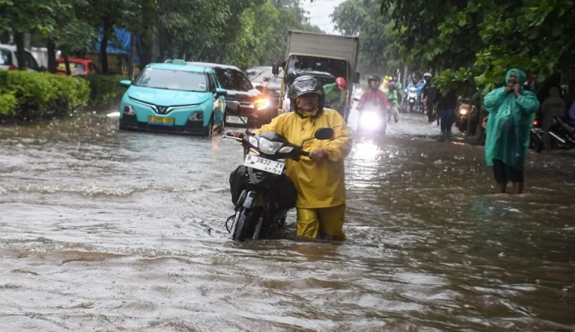 Warga mendorong motornya yang mogok saat melintasi banjir di kawasan Sunter, Jakarta, Senin (12/1/2026).(Muhammad Adimaja)