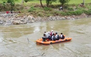 Pelajar Desa Tanjungsari menyeberangi Sungai Cimandiri menggunakan perahu karet, Kamis (22/1). Sejak jembatan gantung roboh diterjang banjir, akses menuju sekolah berubah menjadi pertaruhan nyawa.