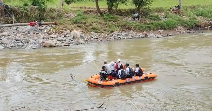 Pelajar Desa Tanjungsari menyeberangi Sungai Cimandiri menggunakan perahu karet, Kamis (22/1). Sejak jembatan gantung roboh diterjang banjir, akses menuju sekolah berubah menjadi pertaruhan nyawa.