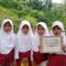 Sejumlah anak di Kampung Babakan, Desa Mekarjaya, Kecamatan Warungkiara, membentangkan poster protes atas kondisi jalan rusak. Warga berharap pemerintah segera melakukan perbaikan. (Foto: Untuk/Radar Sukabumi)