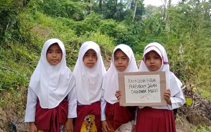Sejumlah anak di Kampung Babakan, Desa Mekarjaya, Kecamatan Warungkiara, membentangkan poster protes atas kondisi jalan rusak. Warga berharap pemerintah segera melakukan perbaikan. (Foto: Untuk/Radar Sukabumi)