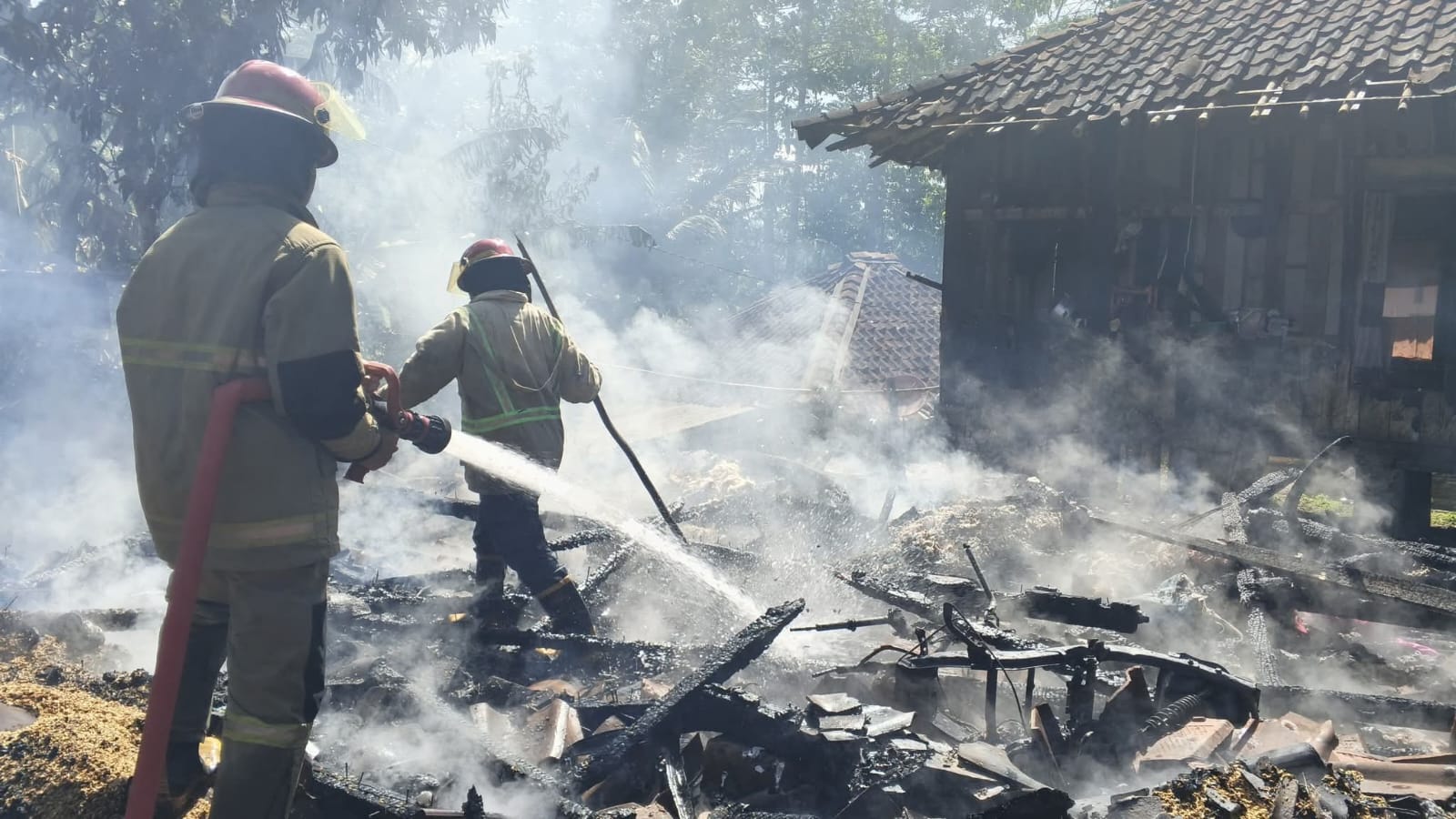 Tim gabungan berusaha memadamkan kobaran api yang melalap tiga rumah panggung di Kampung Ciranjang Sawah, Desa Karangmekar, Kecamatan Cimanggu, Kabupaten Sukabumi. (Foto: Nandi/Radar Sukabumi)