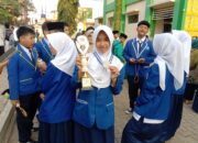 BERPRESTASI: Salah seorang siswi MTsN Kota Sukabumi menunjukkan medali dan trofi yang diraih pada ajang Madrasah Science Olympiad Competition (MASOIC) 2026 tingkat Provinsi Jawa Barat di MTsN 2 Purwakarta, Sabtu (25/7).(dok/radarsukabumi)